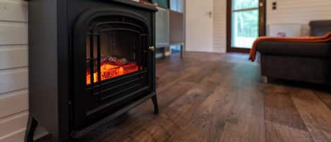 Una estufa de leña en una habitación con suelo de madera y un sofá.