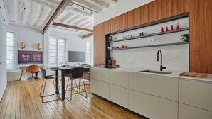 A modern kitchen with wooden accents, a built-in island, and a dining area with a table and chairs. - Amazing 2 Bedrooms Apartement Paris Center (Paris)
