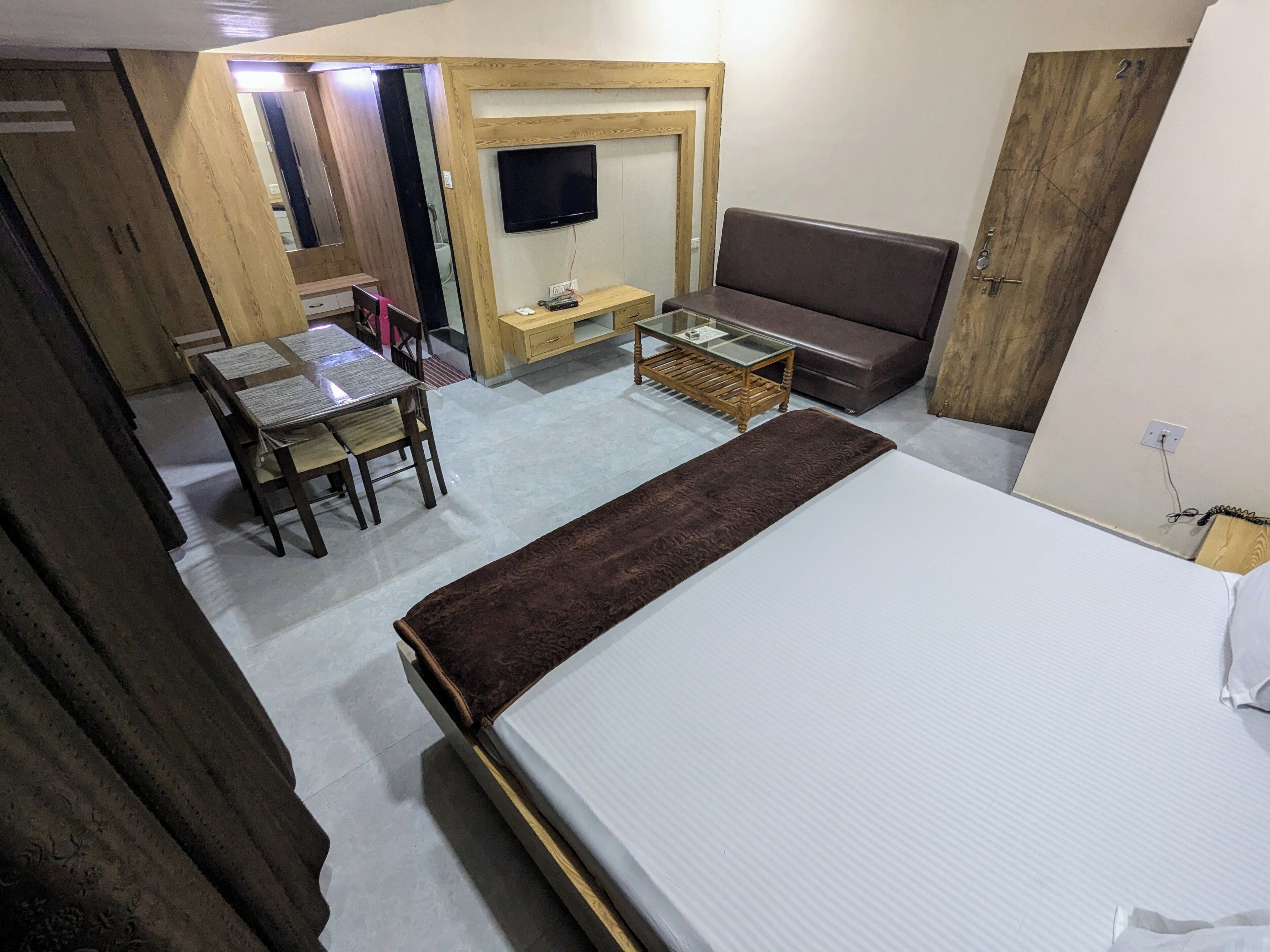 Una habitación compacta con cama, sofá, una mesita y televisor instalado en la pared.