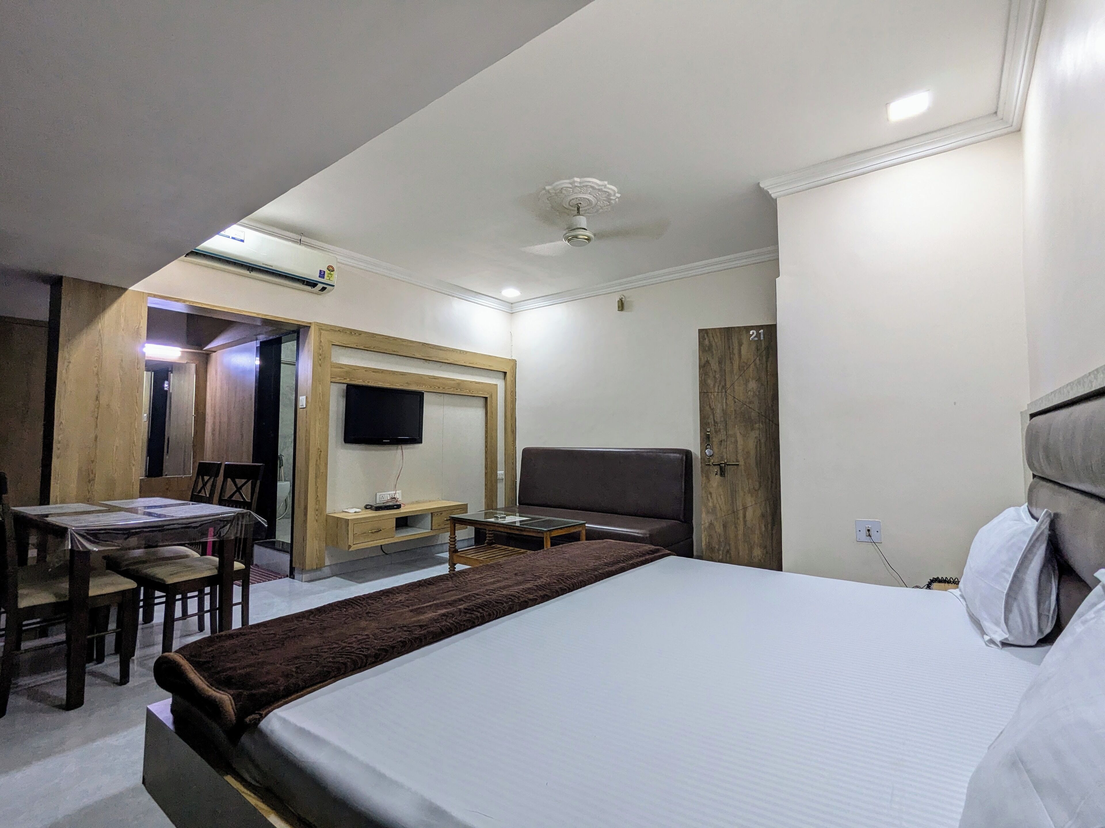 A hotel room with a bed, a desk with a chair, a television, and a wardrobe.