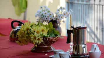 Enjoy a pleasant dining experience in a beautifully set outdoor space with a traditional teapot, coffee maker, and floral arrangement.