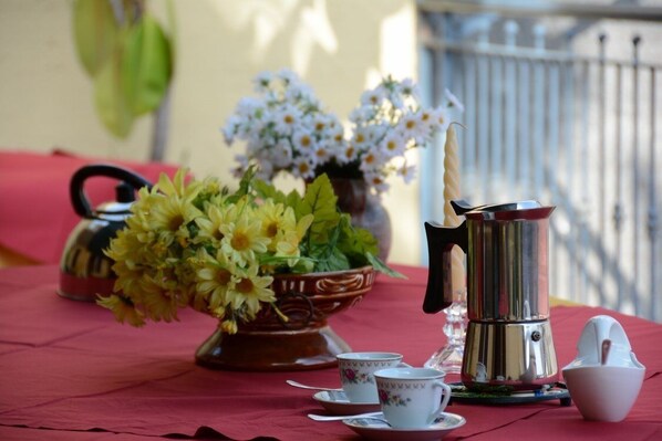 A table set with a teapot, cups, saucers, a sugar bowl, and a vase with flowers. - B&B CASABELLA (Riposto)