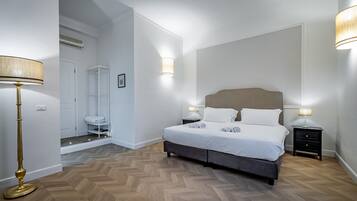 A bedroom with a bed, bedside tables, a floor lamp, and a walk-in closet.