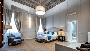 Hotellihuone, jossa on suuri sänky, sohva, tuoli, lamppu ja näkymä ulos.