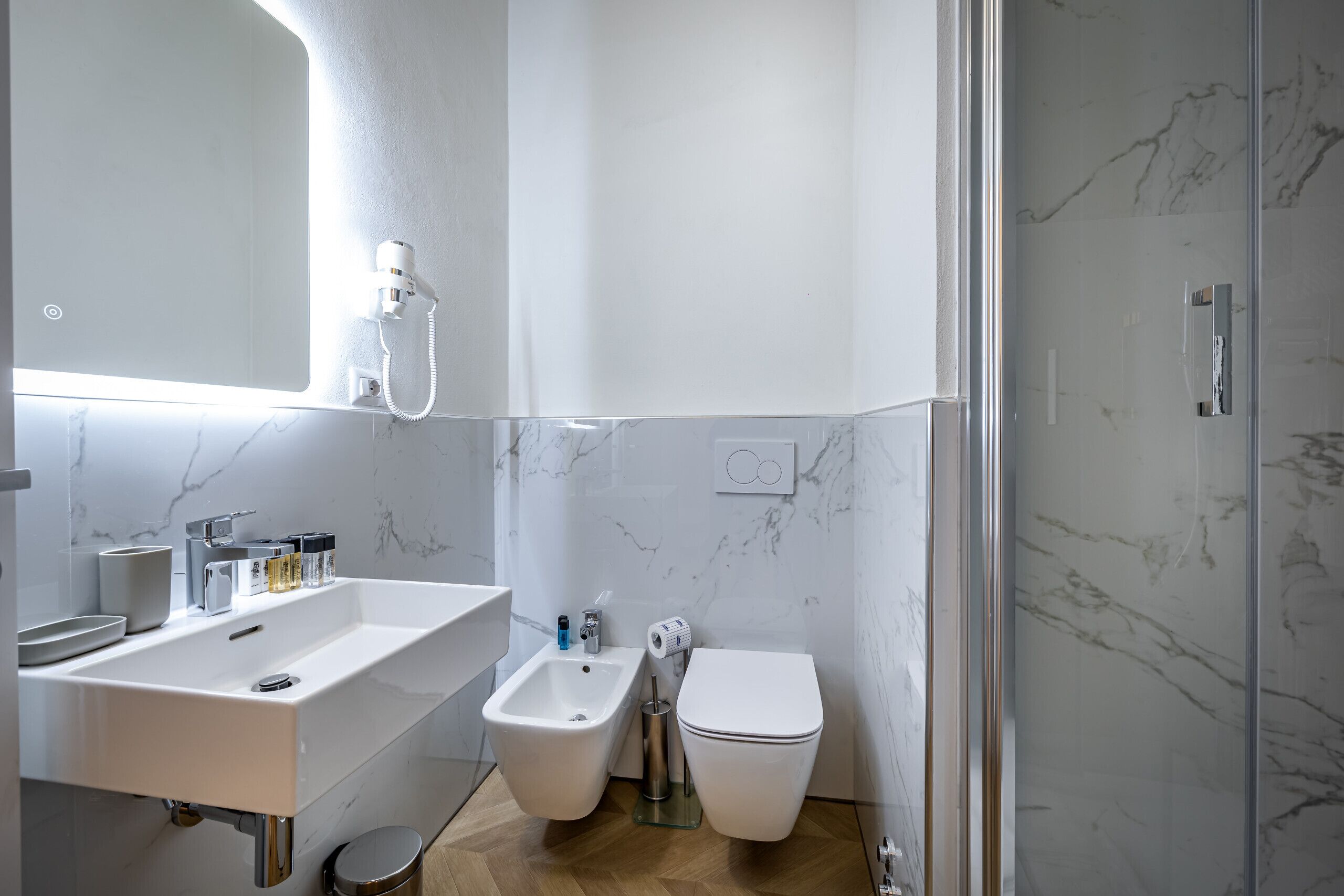 Une salle de bain moderne équipée d’un lavabo, d’un bidet, de toilettes et d’un espace douche.