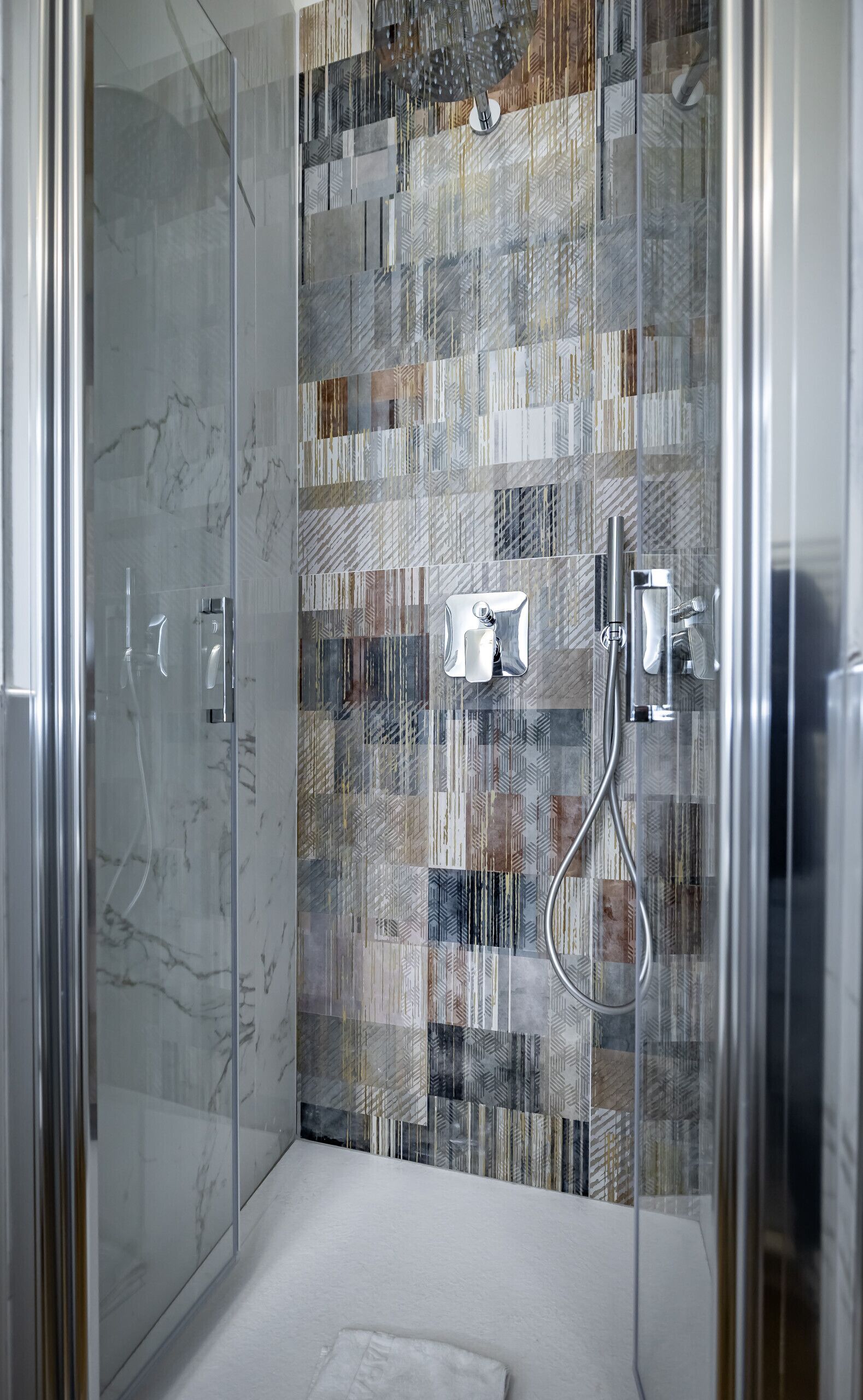 A modern shower with a glass door and a tiled wall.