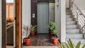 Un hall d’hôtel avec un comptoir d’accueil, un escalier et des plantes en pot.
