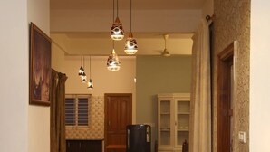 Un couloir bien éclairé, agrémenté d’un lustre, un coin repas avec un buffet et une plante en pot.