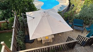 Eine Terrasse mit Pool, Sitzgelegenheiten im Freien und einer Pergola.