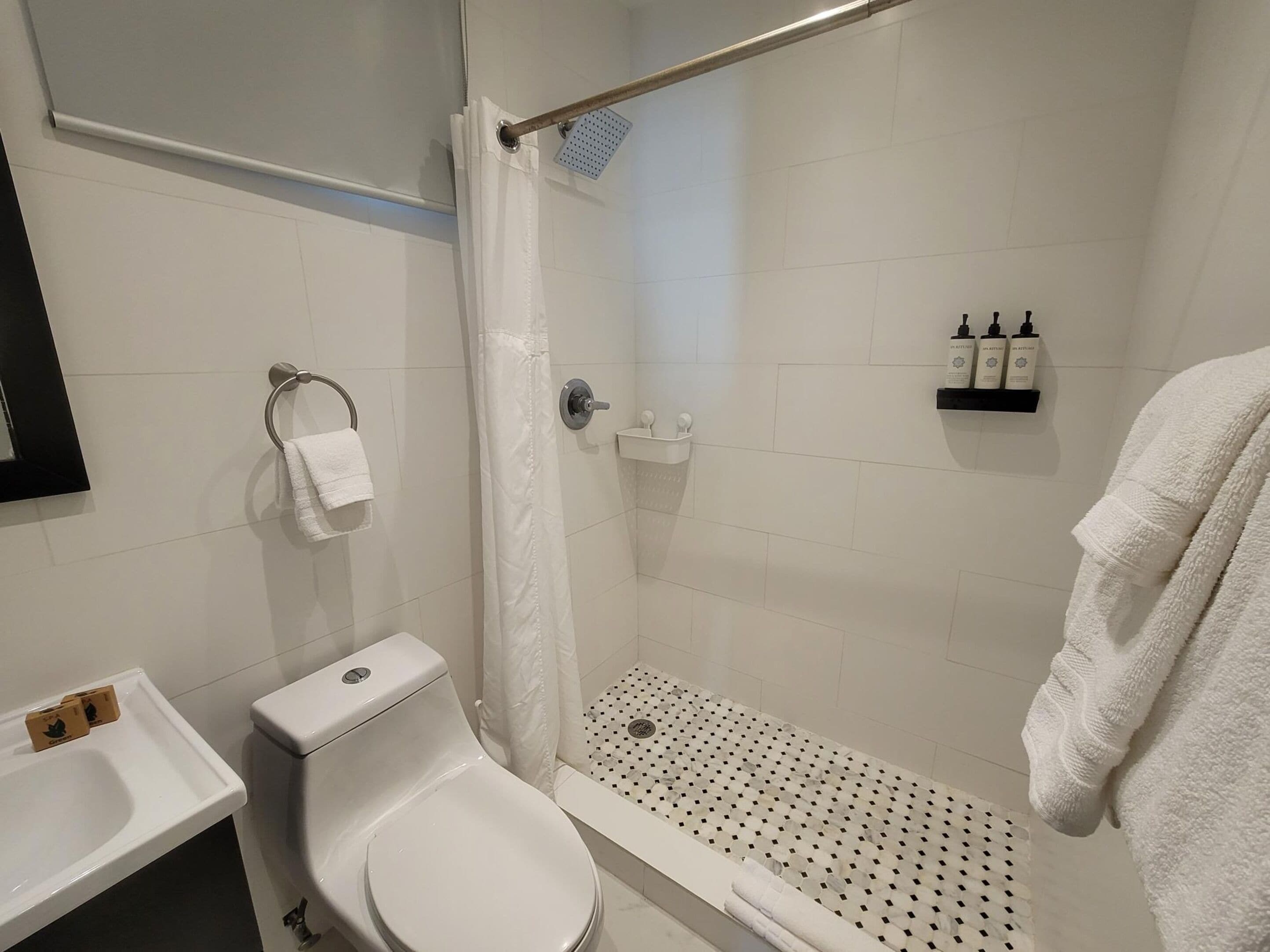 Ein Badezimmer mit Toilette, Waschbecken, Dusche und Handtuchhalter.