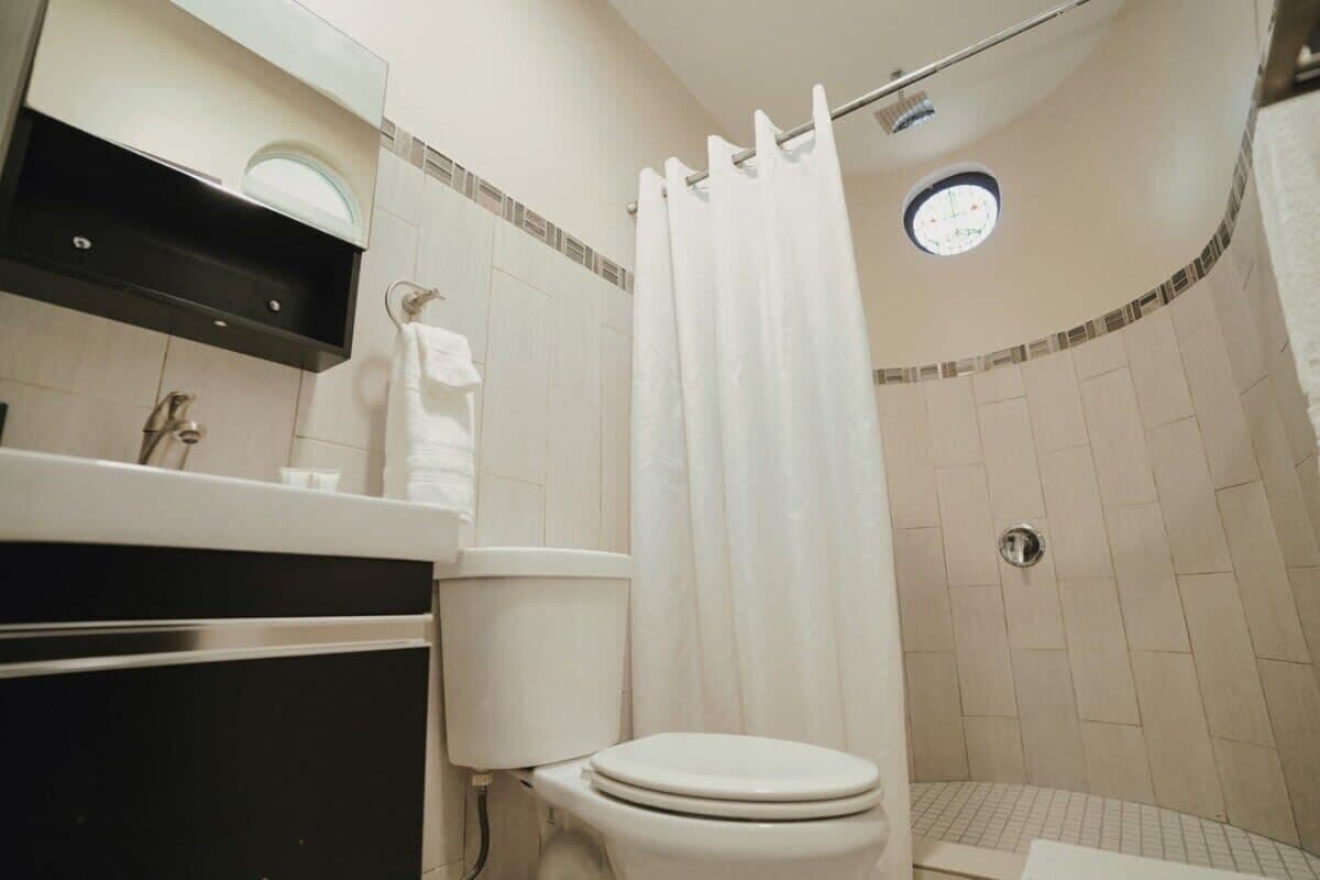 A bathroom with a toilet, sink, and shower area.
