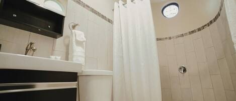 A bathroom with a toilet, sink, and shower area.