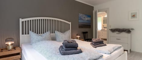 A neatly made bed with a patterned bedspread, pillows, and folded towels.