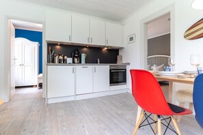 Eine moderne Küche mit weißen Schränken, einer schwarzen Arbeitsplatte und einem roten Stuhl.