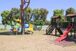 A playground with a slide and climbing structures, surrounded by trees and a clear sky. - Villa in Cecina Mare near Sandy Beaches (Cecina Mare)