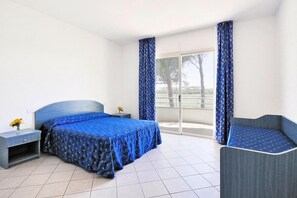A bedroom with a bed, a nightstand, a chair, and a view of the outdoors. - Villa in Cecina Mare near Sandy Beaches (Cecina Mare)