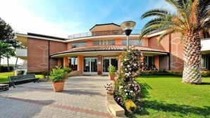 A building with a curved entrance, a paved walkway, and a palm tree. - Villa in Cecina Mare near Sandy Beaches (Cecina Mare)