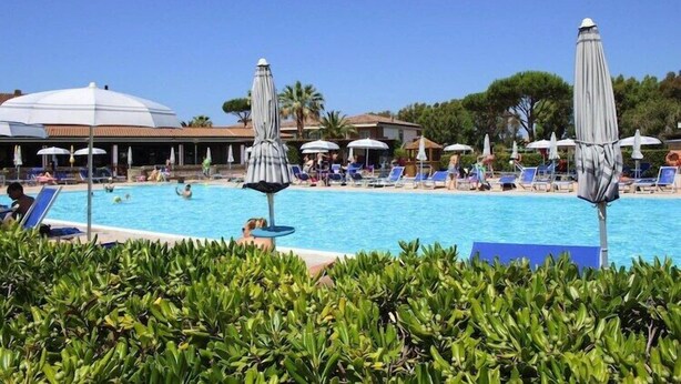 A pool area with lounge chairs and umbrellas, surrounded by greenery. - Villa in Cecina Mare near Sandy Beaches (Cecina Mare)