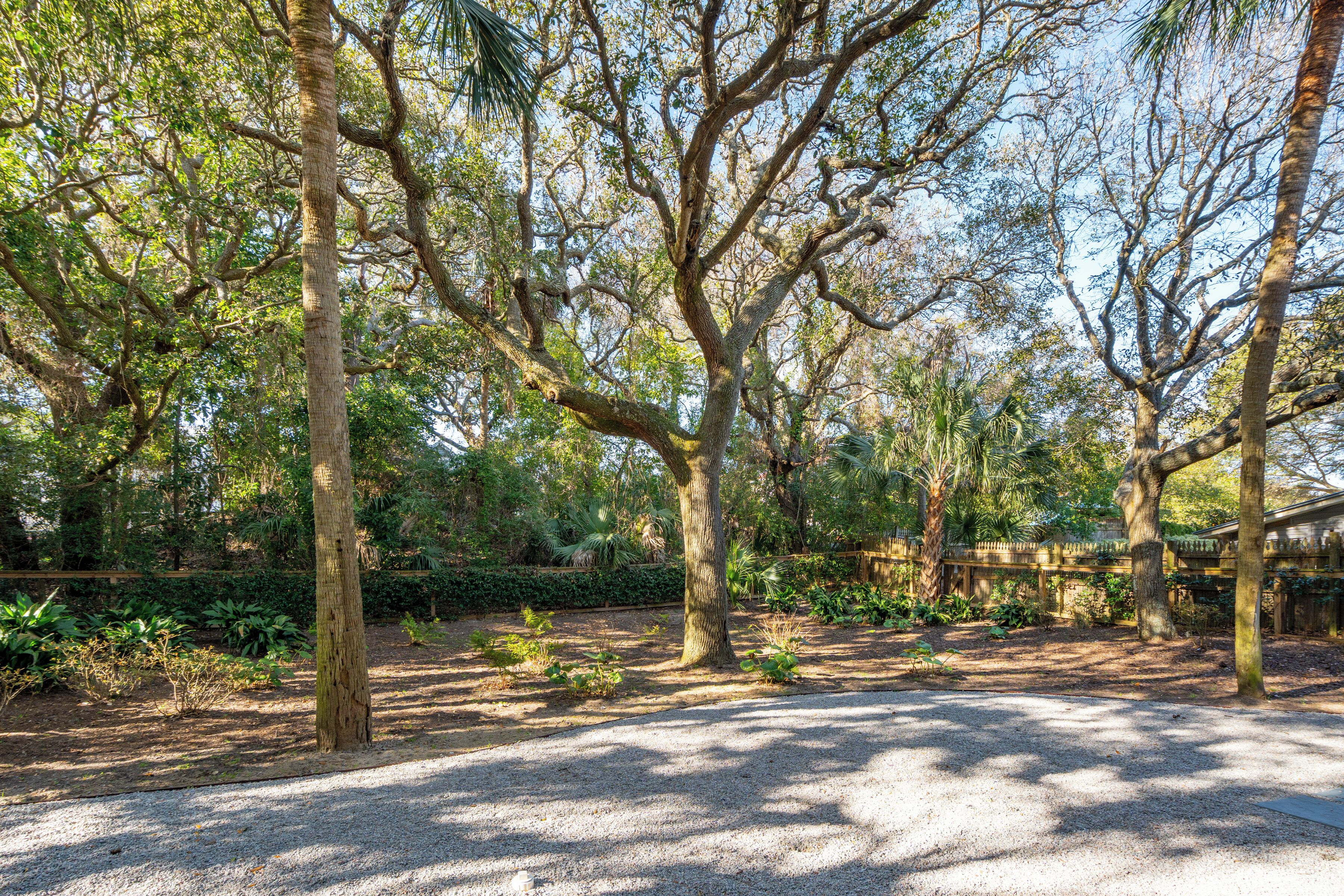 A park with trees, gravel paths, and a wooden fence.