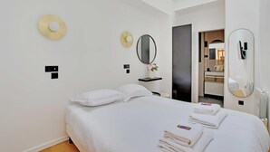 A modern hotel room with a bed, two wall-mounted mirrors, and a small shelf with a vase. - Authentic apt - 2br/6p - Rue des Martyrs - Opera (Paris)