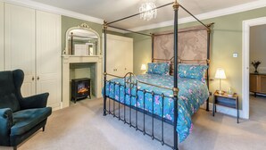 A four-poster bed with floral bedding, a fireplace, a dark armchair, and a chandelier. - Steelclose House - UK48471 (Lintzford, near Rowlands Gill)