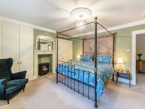 A four-poster bed with floral bedding, a fireplace, a dark armchair, and a chandelier. - Steelclose House - UK48471 (Lintzford, near Rowlands Gill)