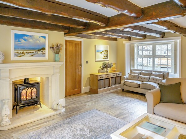 Una sala de estar acogedora con chimenea, un sofá, una mesita de centro y una ventana con vistas.