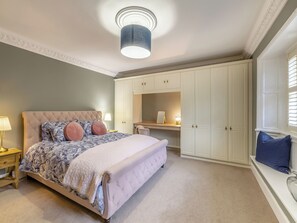 Een slaapkamer met een groot bed, een kledingkast en een bureau met een lamp.