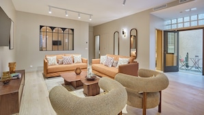 A spacious living room with two sofas, a coffee table, and wicker chairs.
