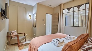 A bedroom with a bed, a chair, a wardrobe, and a mirror.
