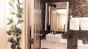 A bathroom with a white sink, a mirror, and a toilet. There is a plant on the left side and a towel rack on the right. - Hostal las Rosas de Punta Cana (Punta Cana)