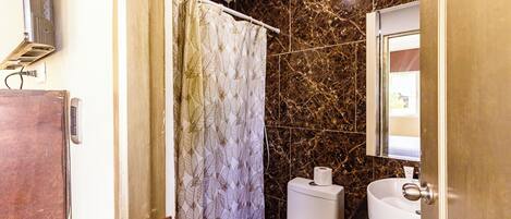 A bathroom with a toilet, sink, and shower curtain.
