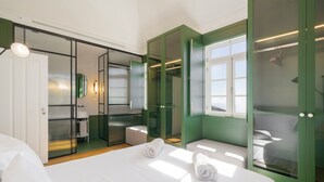 Quarto de hotel moderno com uma cama grande, um closet espaçoso e um banheiro com espelho e pia.