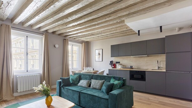 A modern living room with a green sofa, wooden coffee table, and a view of a cityscape through large windows. - Magnificent new Flat Le Marais/beaubourg (Paris)