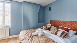 A bedroom with a large bed, a wooden headboard, and a window with a view of buildings. - Magnificent new Flat Le Marais/beaubourg (Paris)