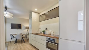A modern kitchen with white cabinetry, a wooden countertop, and a built-in oven. - Apartment in the Center of Paris/montmartre (Paris)