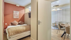 A bedroom with a bed, a door leading to a dining area, and a wall with a decorative piece. - Apartment in the Center of Paris/montmartre (Paris)