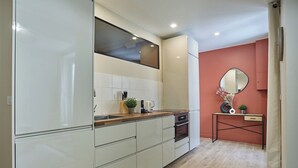 A modern kitchen with white cabinets, a wooden countertop, a built-in oven, and a small table with a mirror and plants. - Apartment in the Center of Paris/montmartre (Paris)