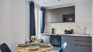 A modern kitchen with grey cabinets, a built-in oven, and a microwave. - Grand Studio Porte Maillot/arc de Triomphe (Paris)