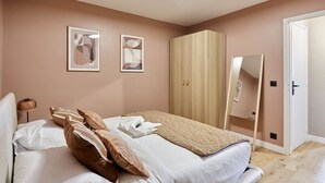 A bedroom with a bed, pillows, a blanket, a wardrobe, a mirror, and artwork on the wall. - Charming new Flat Le Marais/beaubourg (Paris)