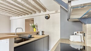 A modern kitchen with a wooden countertop, a sink, and a built-in oven. - Charming new Flat Le Marais/beaubourg (Paris)