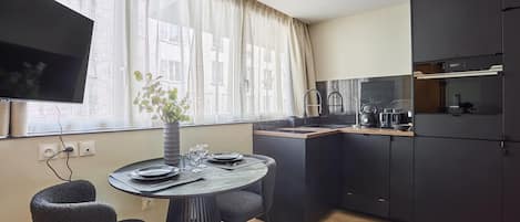 Una cocina moderna con comedor, televisor de pantalla plana y planta en maceta.