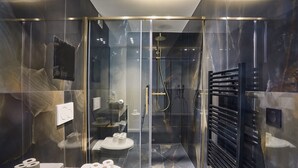 Un bagno moderno con cabina doccia in vetro, un portascopino nero e due servizi igienici con carta igienica.