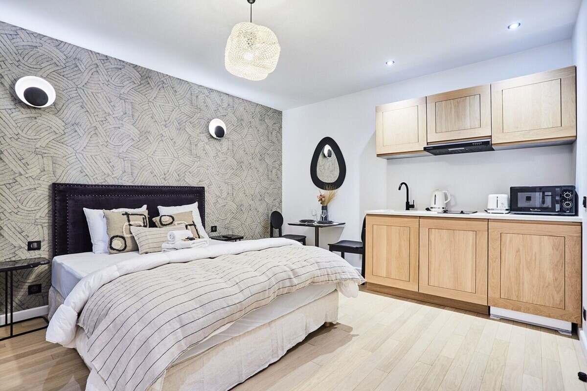 Une chambre moderne avec un grand lit, un petit bureau et un coin cuisine.