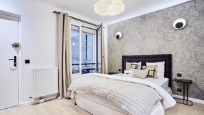 A modern bedroom with a large bed, a window with curtains, a radiator, and a patterned wall. - Superb New Studio in the Center of Paris/opera (Paris)