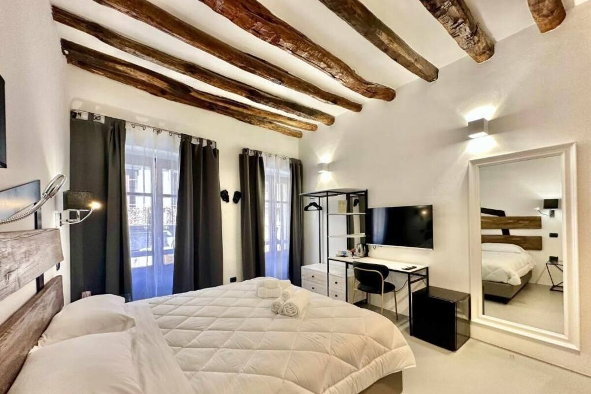 Een slaapkamer met een bed, bureau, stoel, televisie en spiegel.