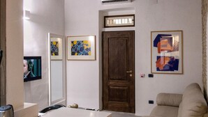 A modern room with a kitchenette, a wooden door, and artwork on the walls.