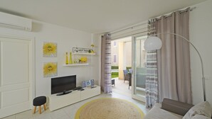 A modern living room with a TV, sofa, and a dining area visible through the glass door. - Le Corti Caterina C3 by Wonderful Italy (Lonato del Garda)
