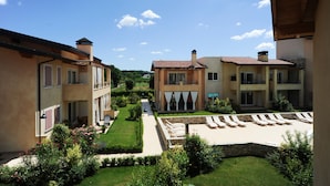 A courtyard with a pool, lounge chairs, and a well-maintained garden. - Le Corti Caterina C3 by Wonderful Italy (Lonato del Garda)