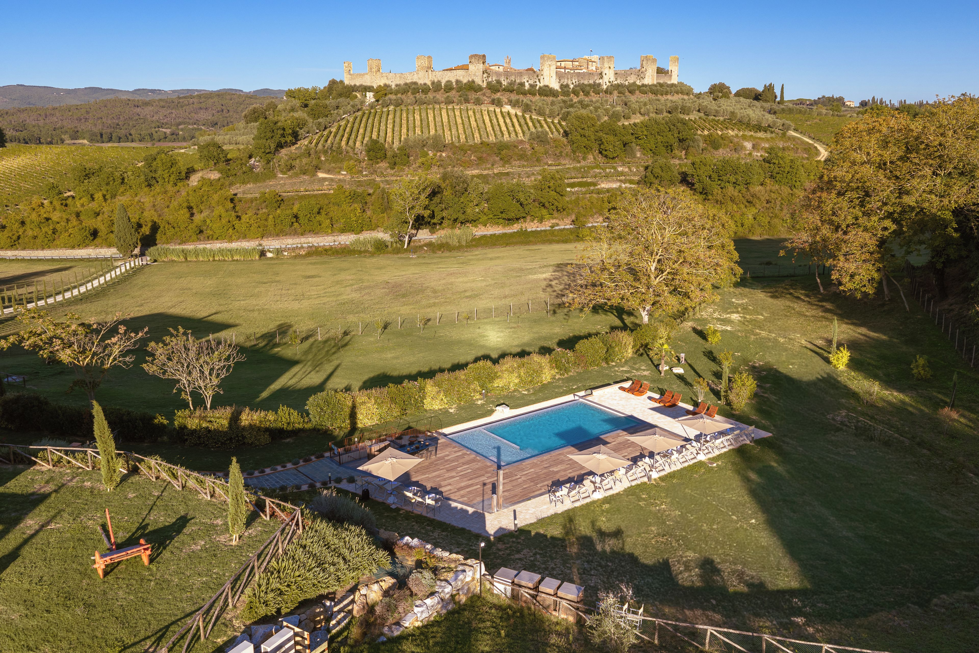 Une piscine avec des chaises longues et une vue sur un château perché sur une colline.